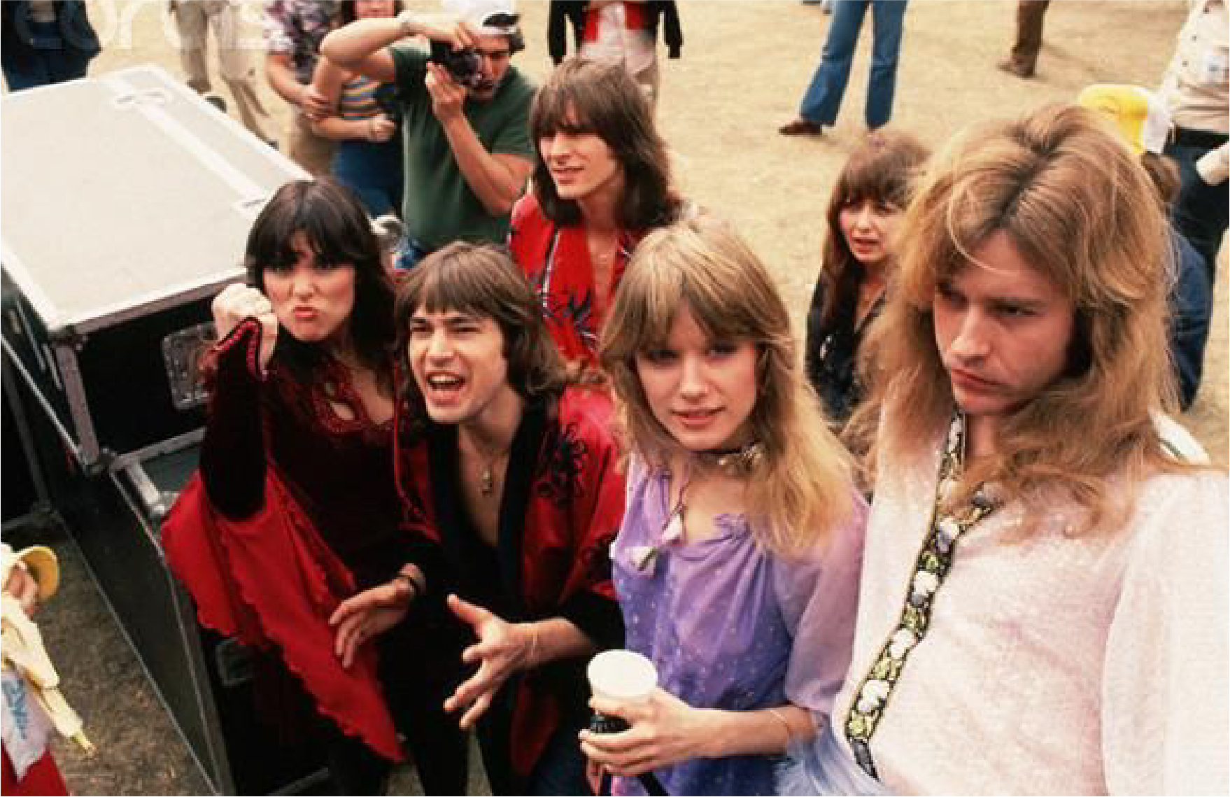 70's photo of the band hanging out and making silly faces outside near fans