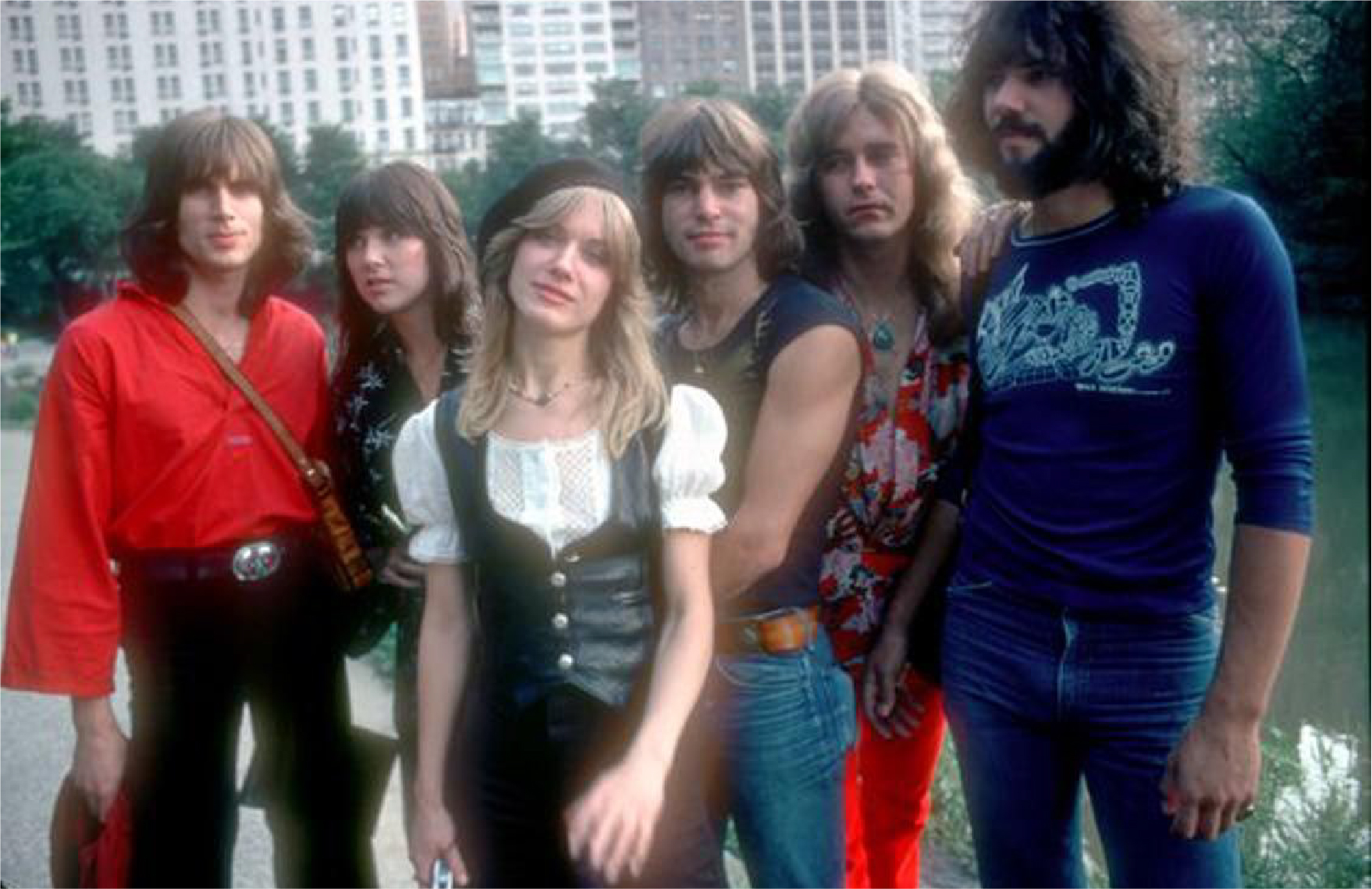 70's photo of the band in a city park by a lake